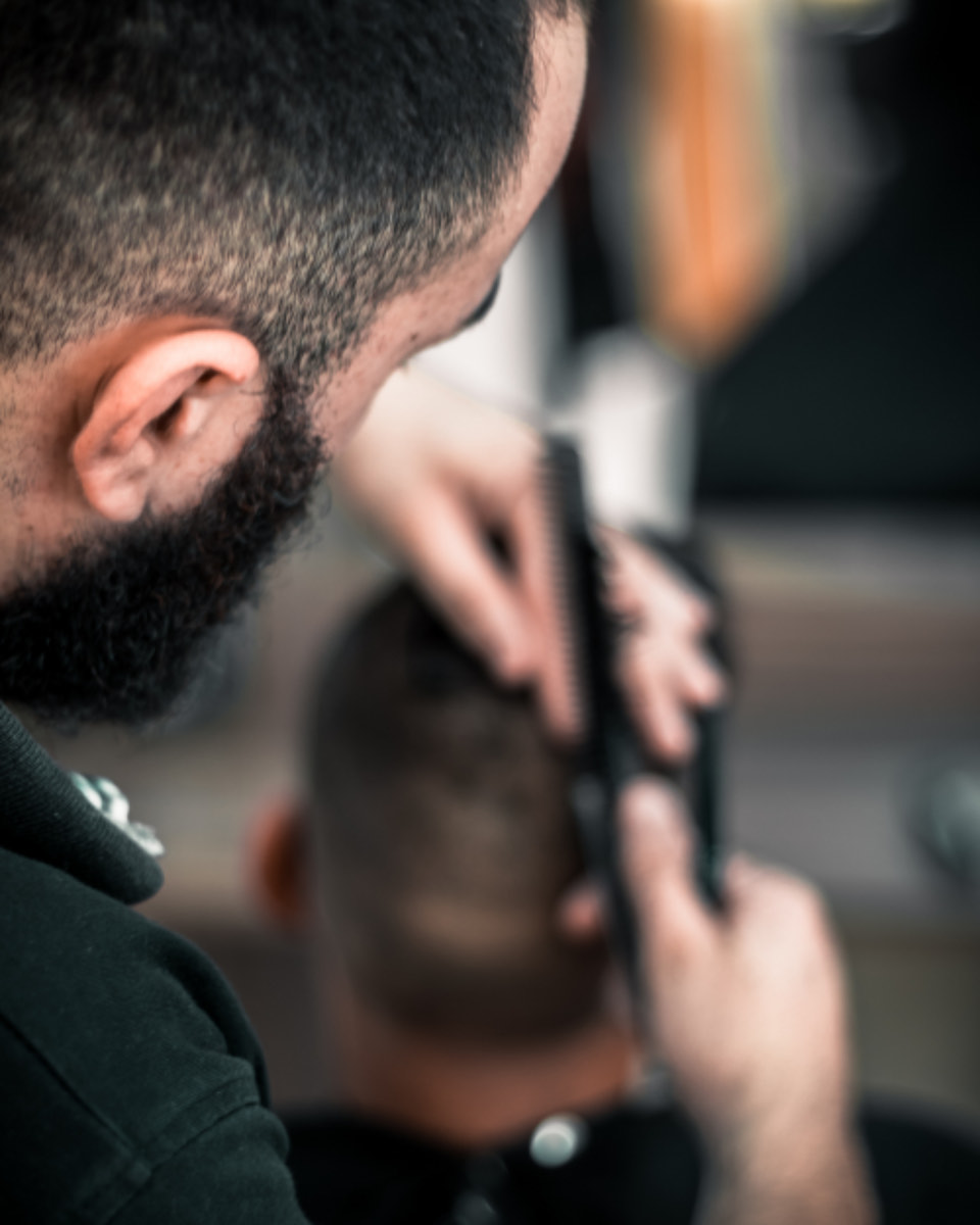 Kapper knipt met tondeuse en kam in de nek van een klant